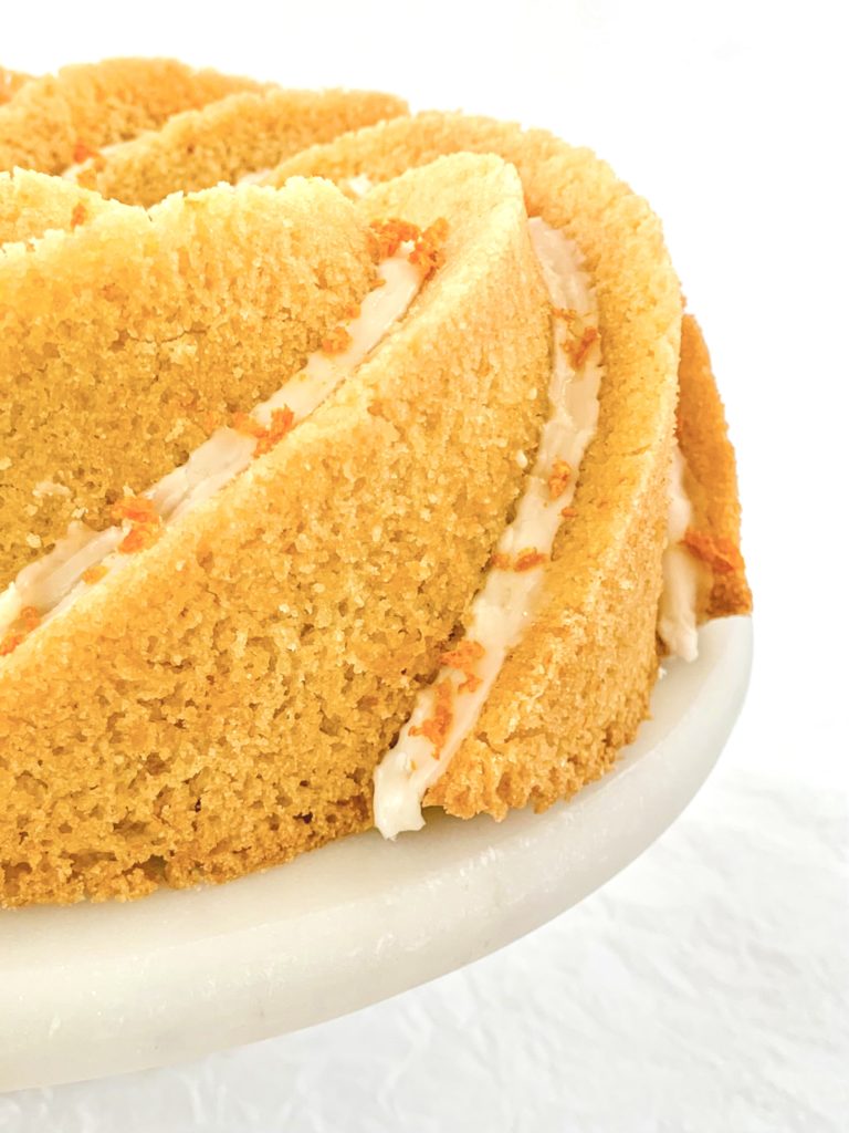 Extreme close up of one side of the bundt cake covered in icing and orange zest