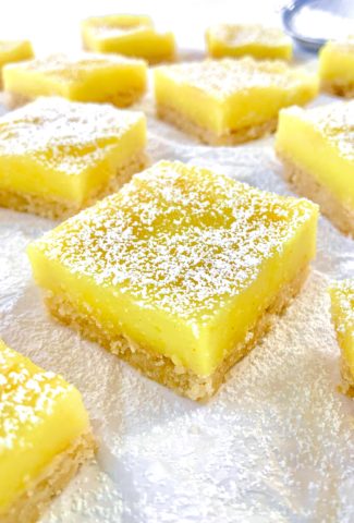 Artistic photo of many lemon bars on a white background, dusted with powdered sugar