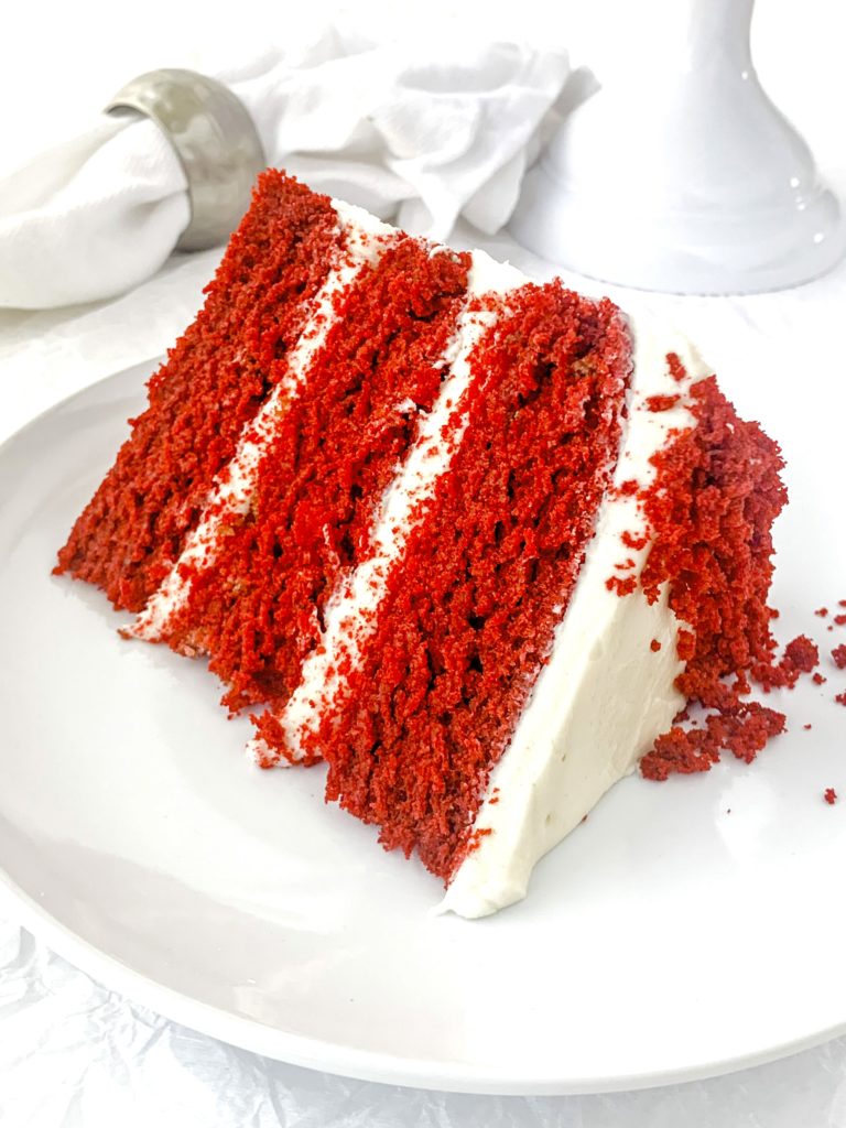 Photo of a big slice of red velvet cake on a white plate