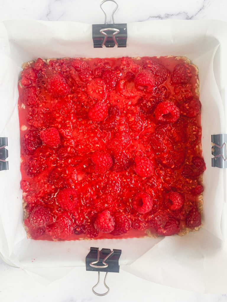 The bars being put together in the pan, now with the berry mixture layered on