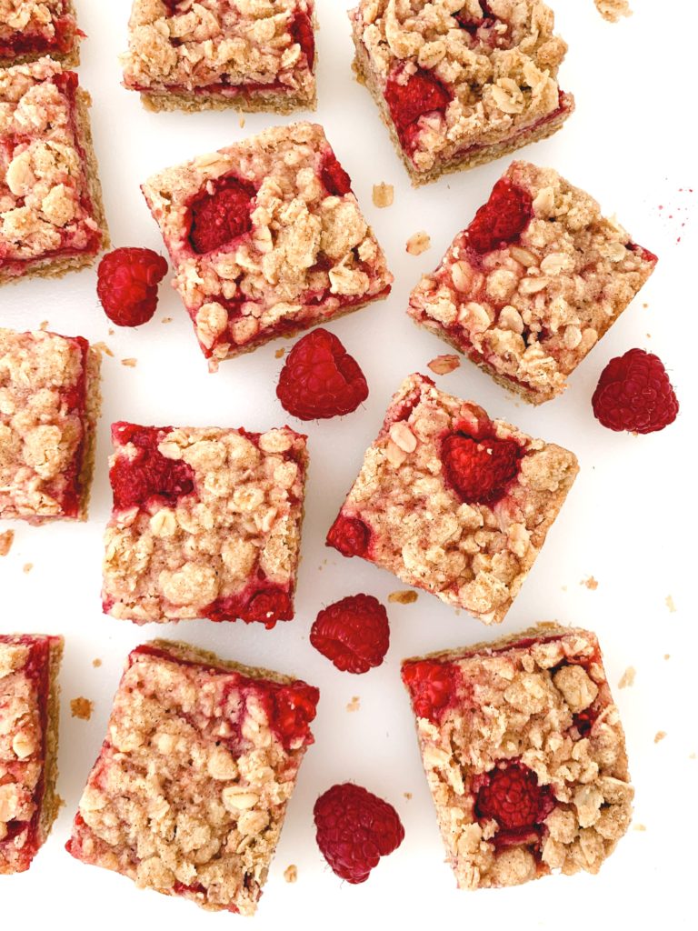 Looking down on a bunch of bars scattered around a white background with fresh raspberries