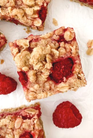 Close up of one bar on a white background with the crumble top and one raspberry poking through