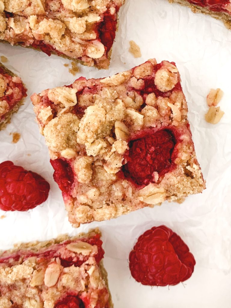 Close up of one bar on a white background with the crumble top and one raspberry poking through