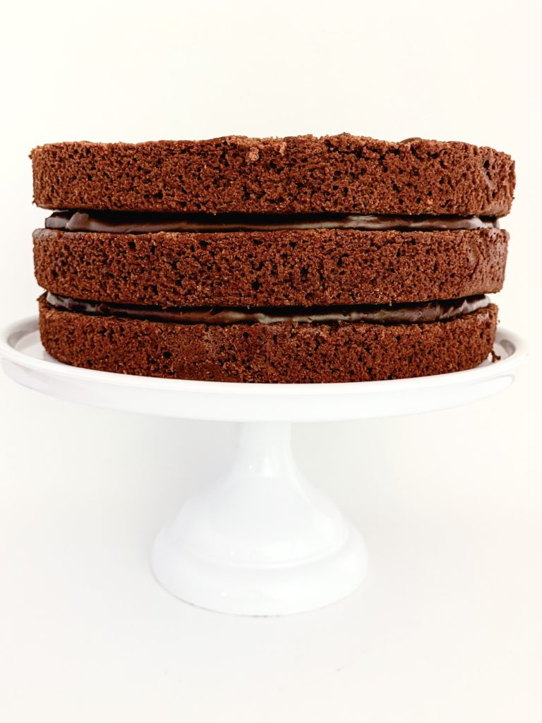 Photo of three layers of chocolate cake with chocolate ganache between the layers