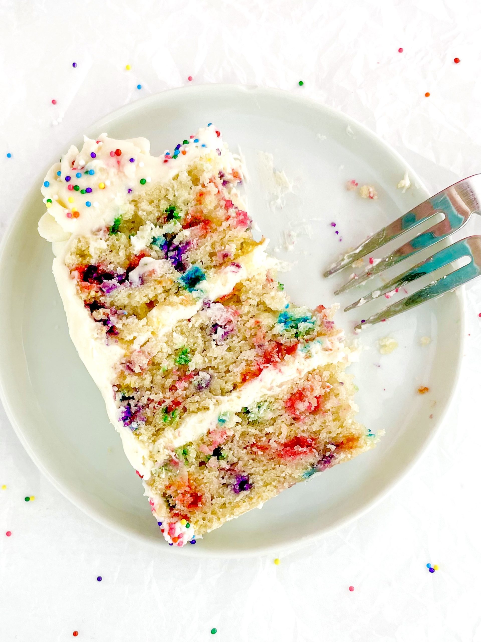 Vegan Funfetti Cake - looking down on one thin slice on a small plate next to a fork