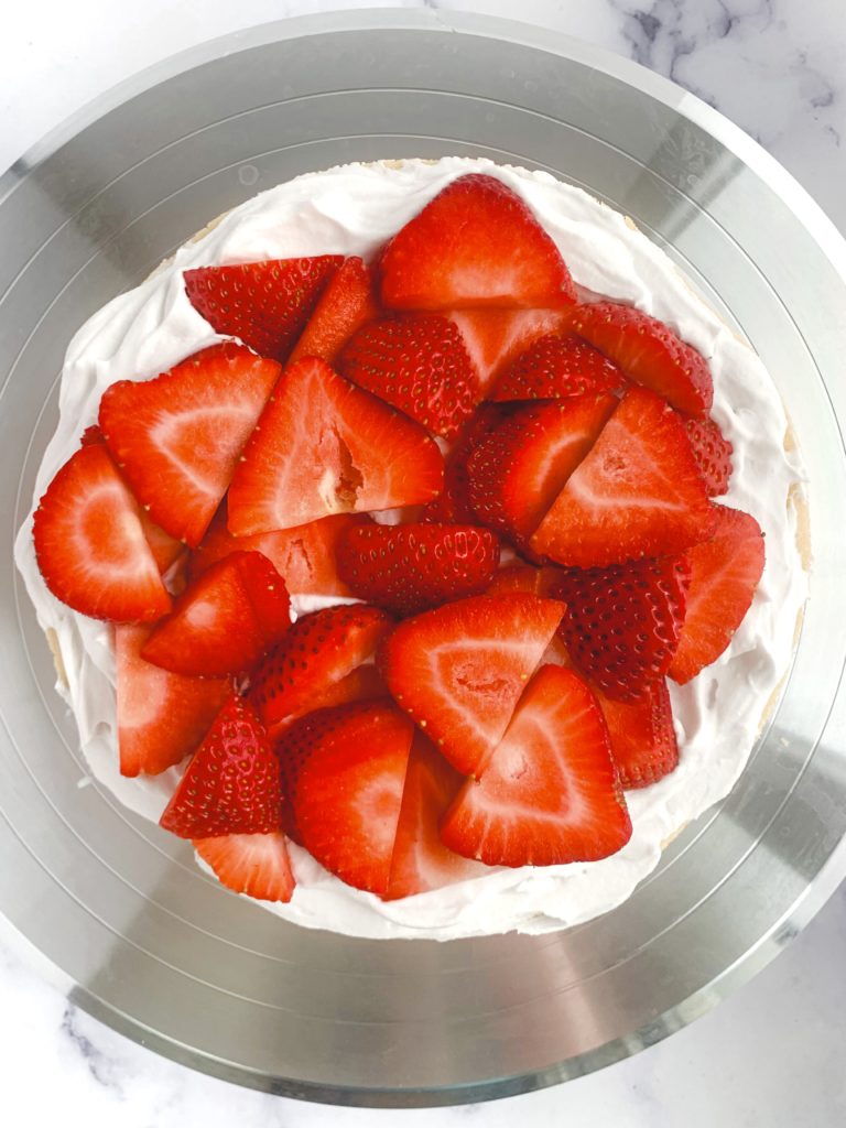 Looking down on a layer of sliced strawberries on top of whipped cream