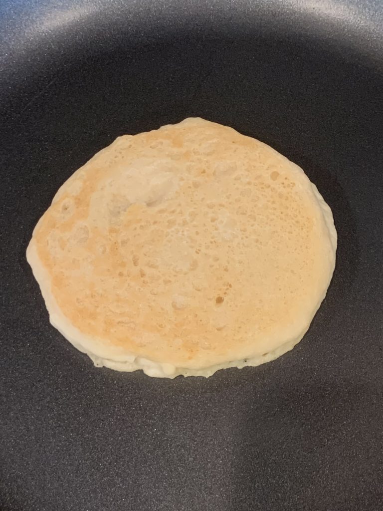 Buttermilk pancake with the top side cooked, still on the pan