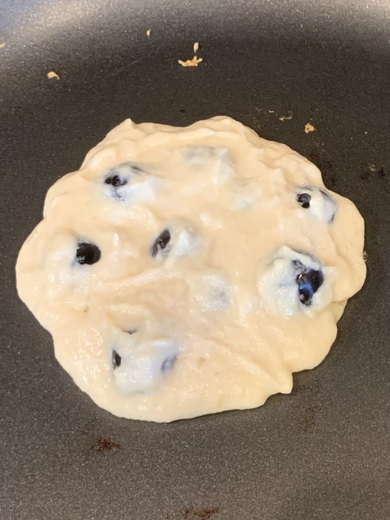Blueberry pancake batter uncooked on the pan